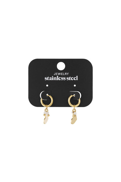 Gold-tone stainless steel hoop earrings featuring dangling heart charms with small white accents on a display card.