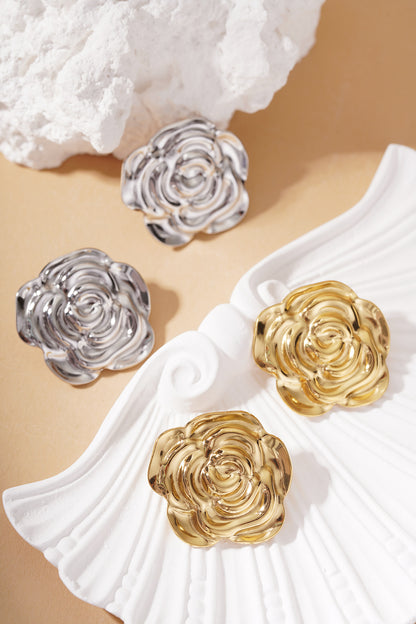 Bloom Core Studs: Two pairs of metallic rose-shaped earrings in polished gold and silver finishes on a shell dish.