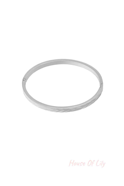 Silver-tone stainless steel bangle bracelet with embossed herringbone pattern on white background