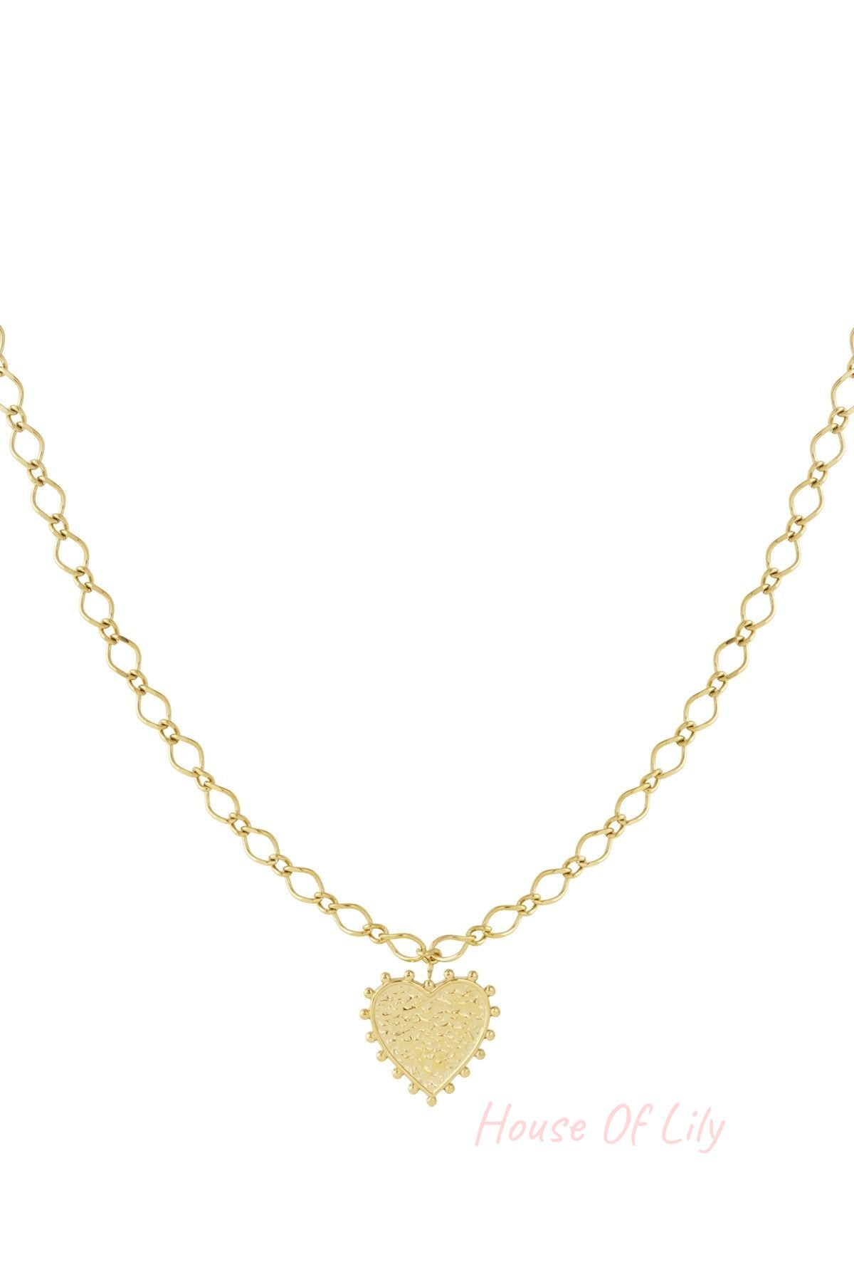 Close-up of a gold-tone heart pendant necklace with textured surface and bead accents on a twisted chain, isolated on white background