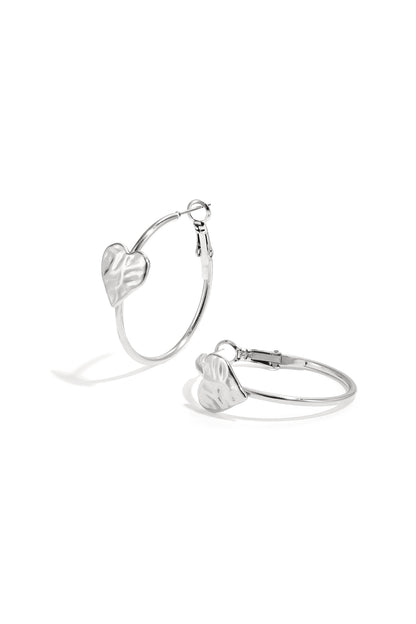 Silver hoop earrings with textured heart detail on white background