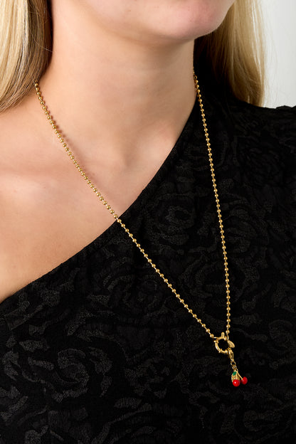 Model wearing gold bead chain necklace with cherry charm pendant over black top