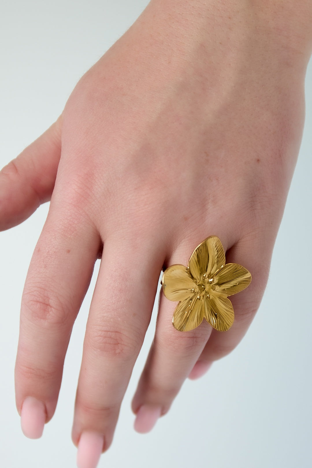 Gold flower statement ring worn on hand showcasing size and design