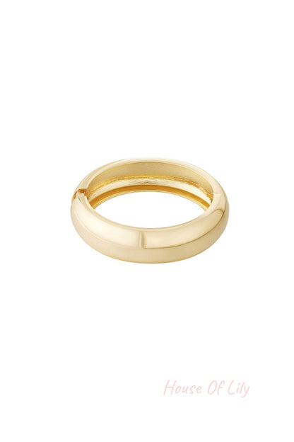 Close-up of a sleek, polished chunky gold bangle bracelet on a white background