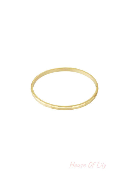 Single geometric faceted gold bangle isolated on white background