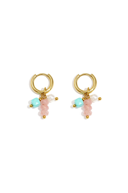 Pair of gold hoop earrings adorned with pink, turquoise, and pearl beads laid flat on white background