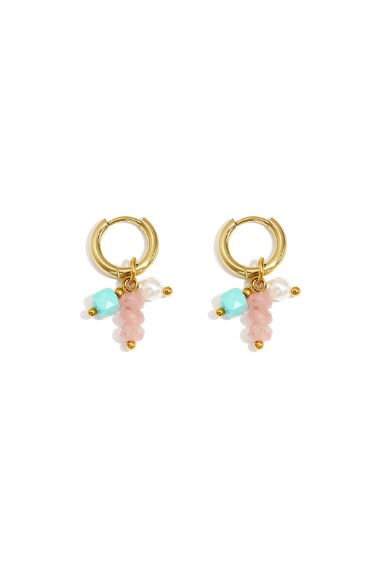 Pair of gold hoop earrings adorned with pink, turquoise, and pearl beads laid flat on white background