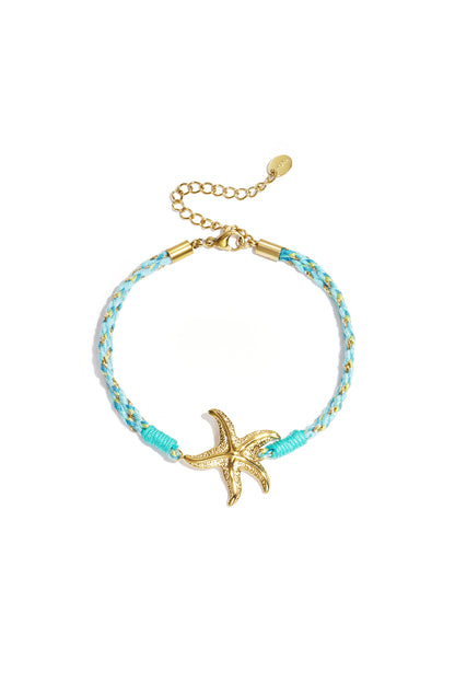 Close-up of pink and white braided rope bracelet with gold sun and moon charm on white background