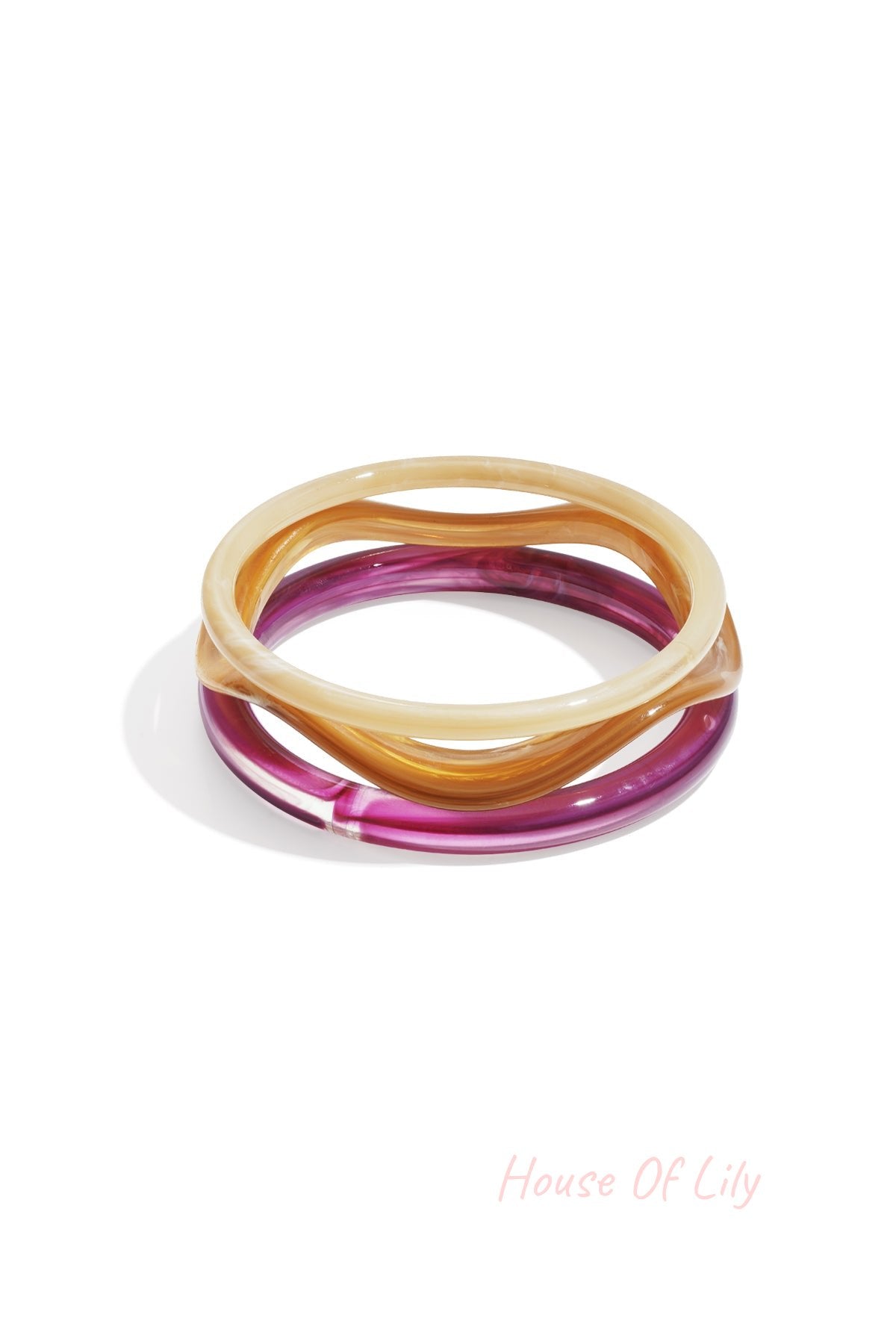 Set of three wavy acrylic bangles in translucent cream, amber, and deep magenta with a smooth, glossy finish.