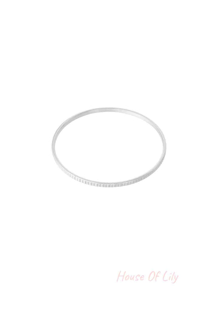 Sleek silver textured bangle bracelet isolated on white background