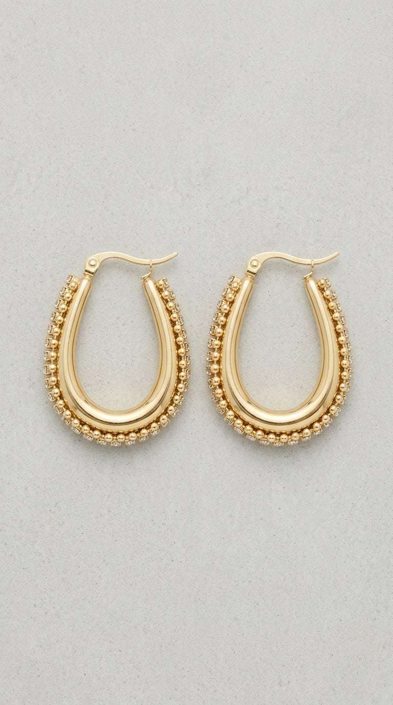 Drip Drop Glow: Gold oval hoop earrings featuring a polished center band framed by delicate beaded crystal edges.