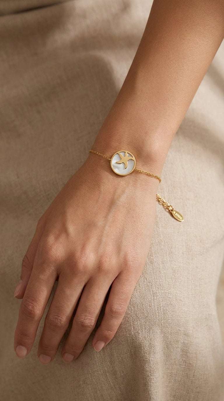 Gold chain bracelet featuring a round pendant with a white mother-of-pearl inlay and a gold starfish silhouette.