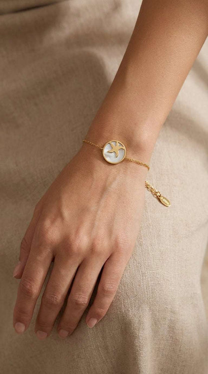 Gold chain bracelet featuring a round pendant with a white mother-of-pearl inlay and a gold starfish silhouette.