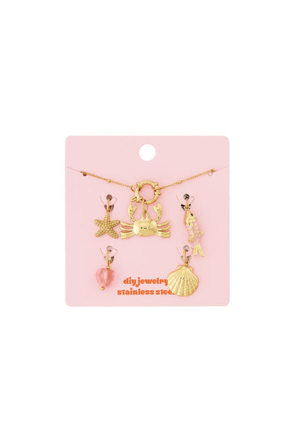 Gold stainless steel charm bracelet kit with crab, starfish, fish, shell, and heart charms on a pink display card.