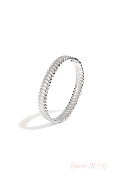 Close up of silver textured ribbed bangle jewelry on white background