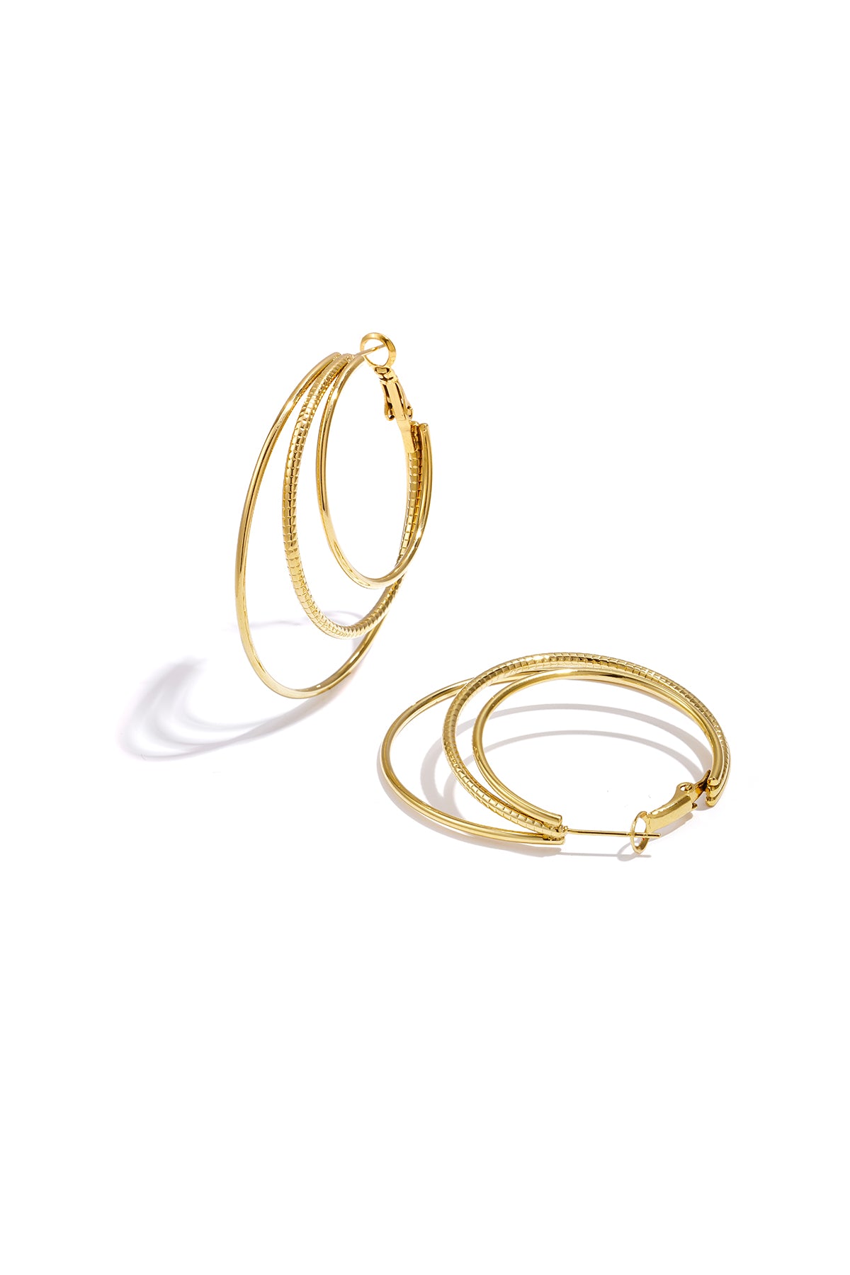 Close-up of gold triple layered hoop earrings on white background with three nested hoops showing smooth and textured finishes