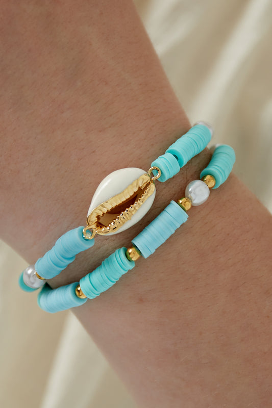 Turquoise shell beaded bracelet set worn on wrist with gold-trimmed shell centerpiece and delicate faux pearls