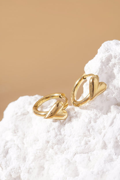 Gold Main Character Heart Hoops featuring chunky puffed heart charms on thin gold huggie hoops on a white stone base.