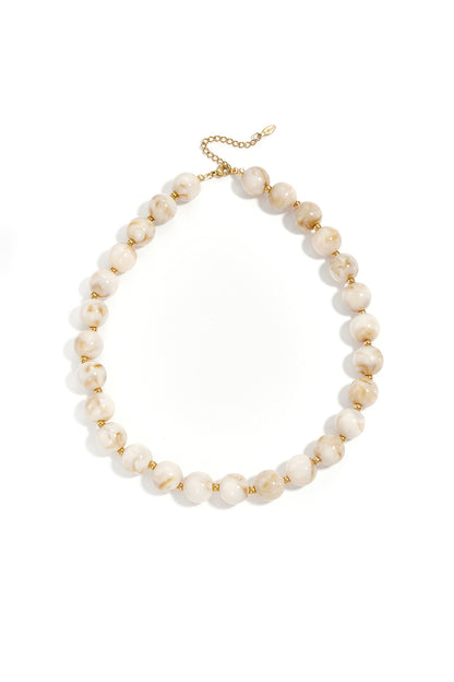 Yellow marbled chunky beaded necklace with gold spacer beads and adjustable gold chain on white background