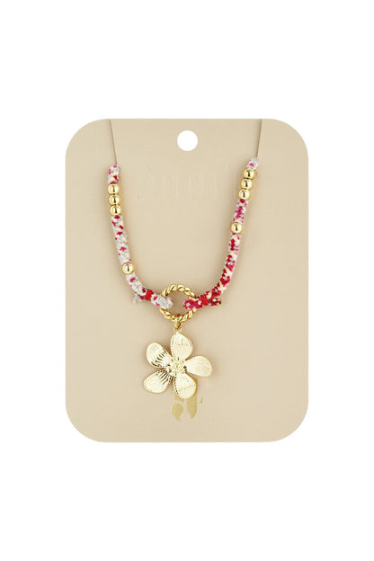 Chic Bloom Drop necklace features a gold flower charm on a pink/white cord with gold beads, on a beige display card.