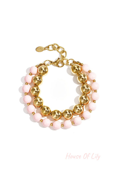 Double layered bracelet with soft pink acrylic and gold-tone beads on white background