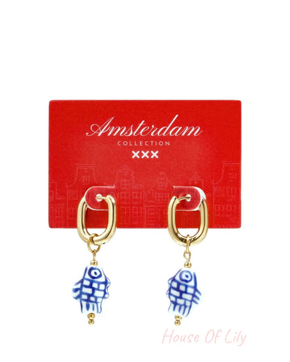 Gold squoval hoop earrings with dangling blue-and-white checkered ceramic fish charms.