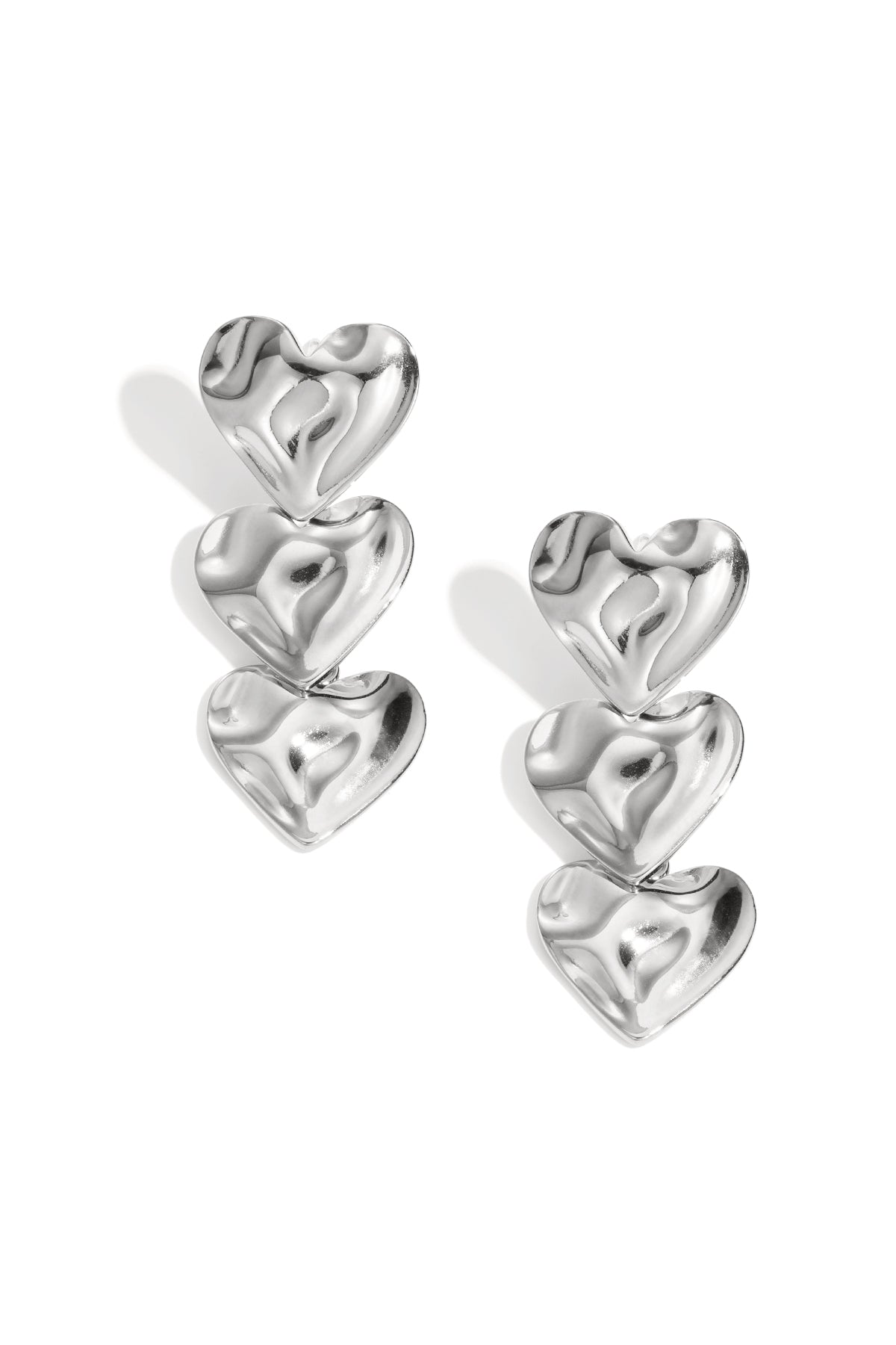 Pair of shiny silver triple heart dangle earrings with soft wave texture on a white background