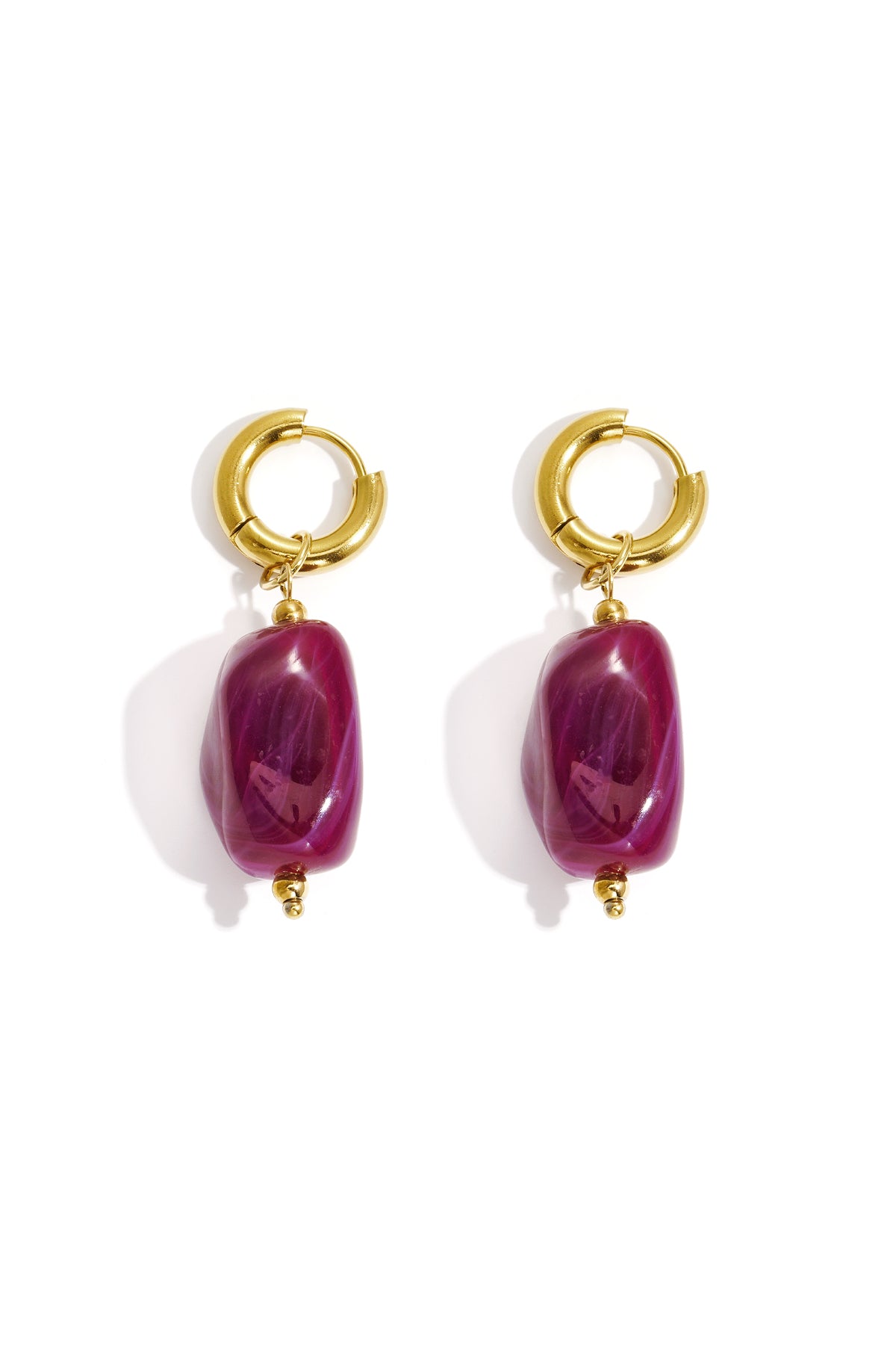 Gold hoop earrings with irregular deep pink resin drop beads on white background