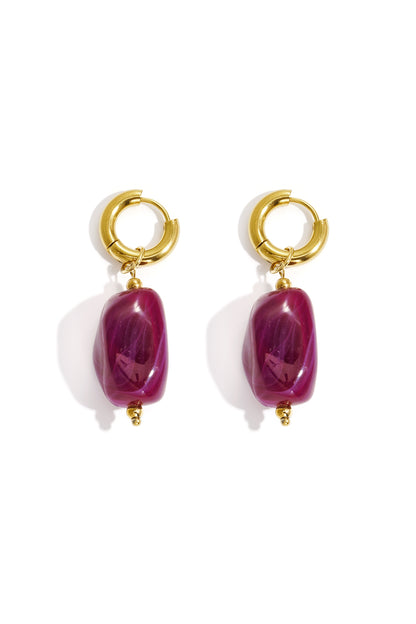 Gold hoop earrings with irregular deep pink resin drop beads on white background