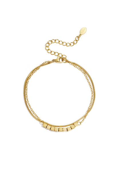 Gold-toned dainty cube chain bracelet with adjustable clasp laid flat on white background