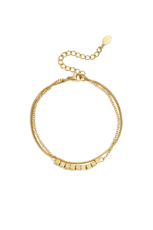 Gold-toned dainty cube chain bracelet with adjustable clasp laid flat on white background