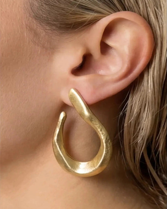 Gold hoop earring worn by a person with blonde hair.
