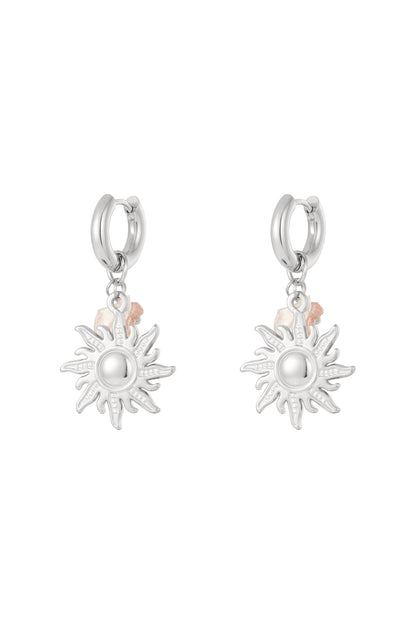 Pair of silver sun charm drop earrings with pink bead accents displayed on white background