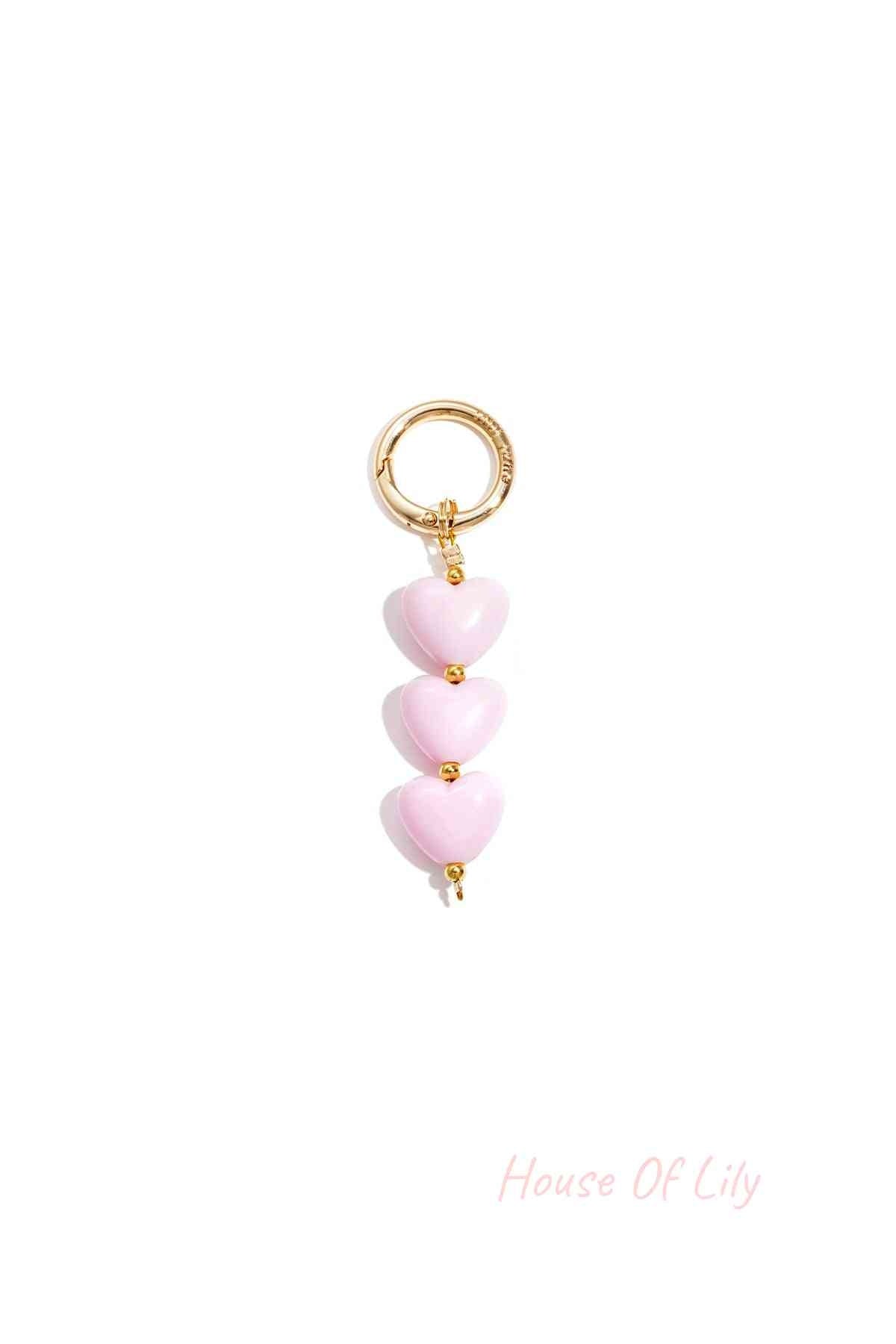 Soft pink acrylic heart charm bag keychain with gold-tone clasp on white background