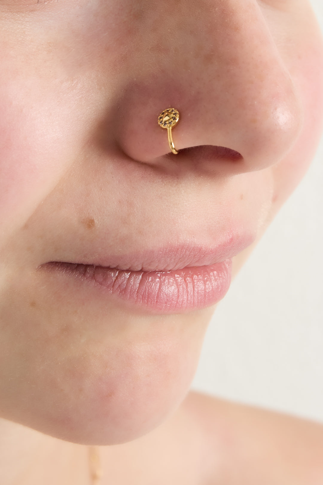 Close-up of a woman wearing the gold-toned triangle zircon nose cuff on her nose