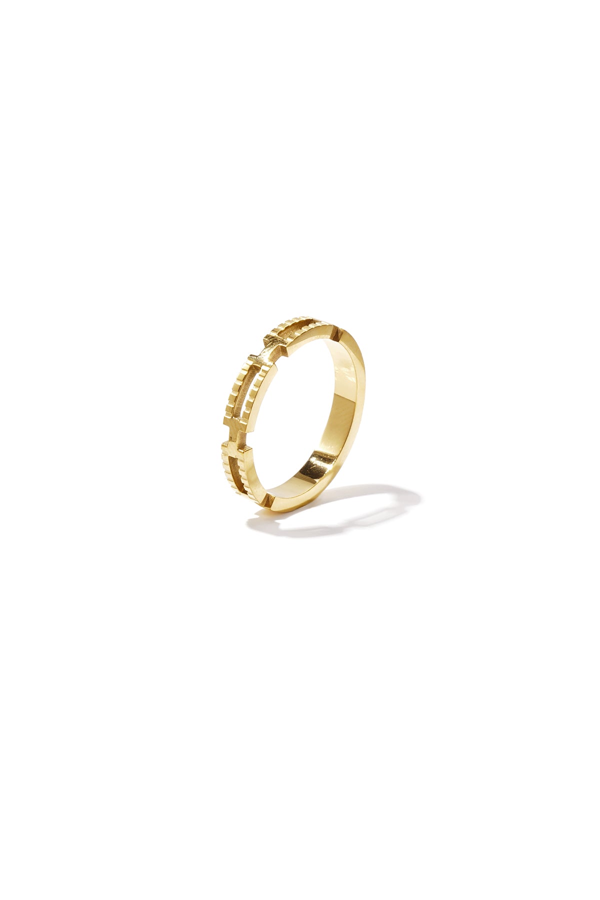 Close-up of a geometric textured gold ring on white background