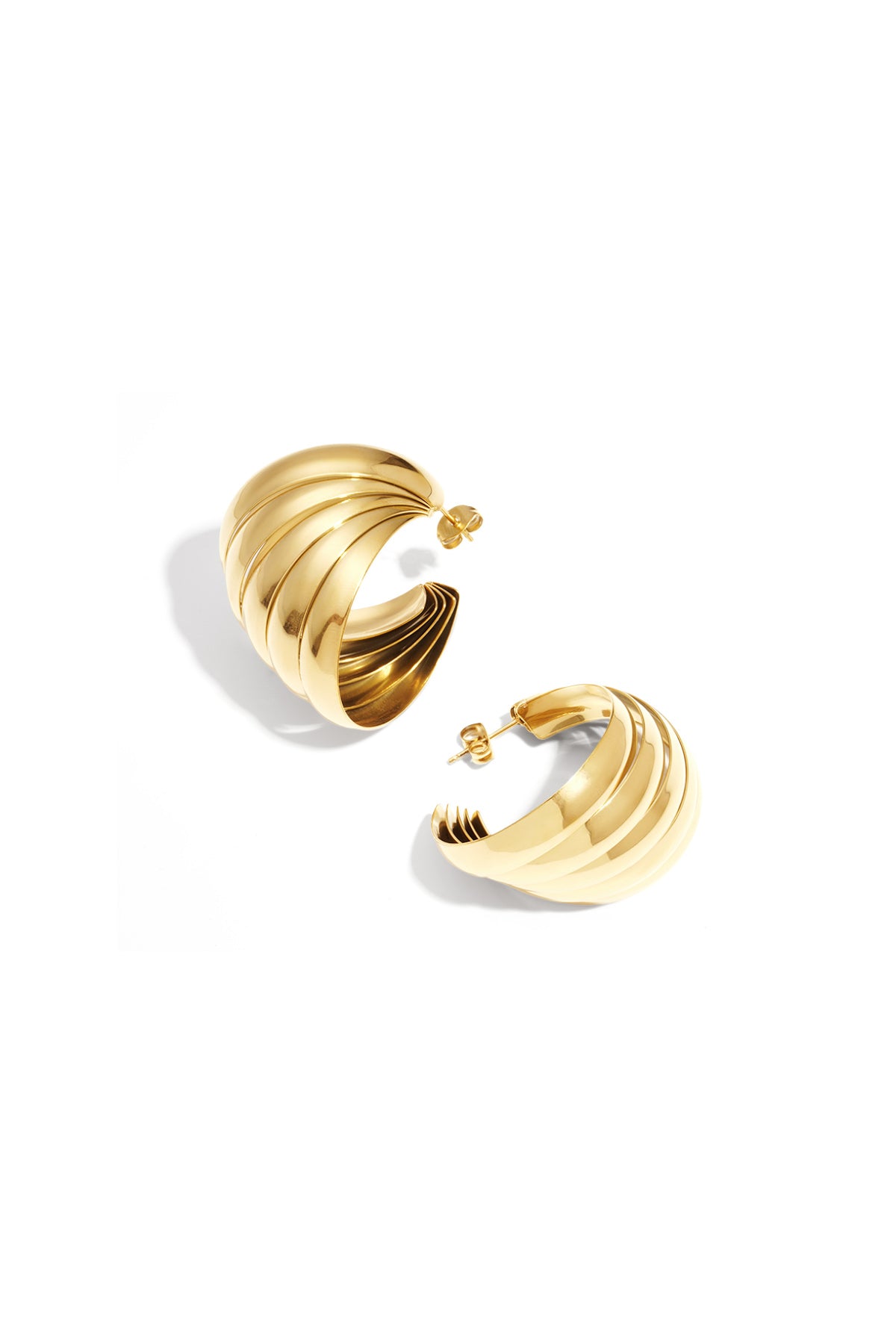 Pair of sculpted hoop earrings with layered ripples in polished gold finish on white background