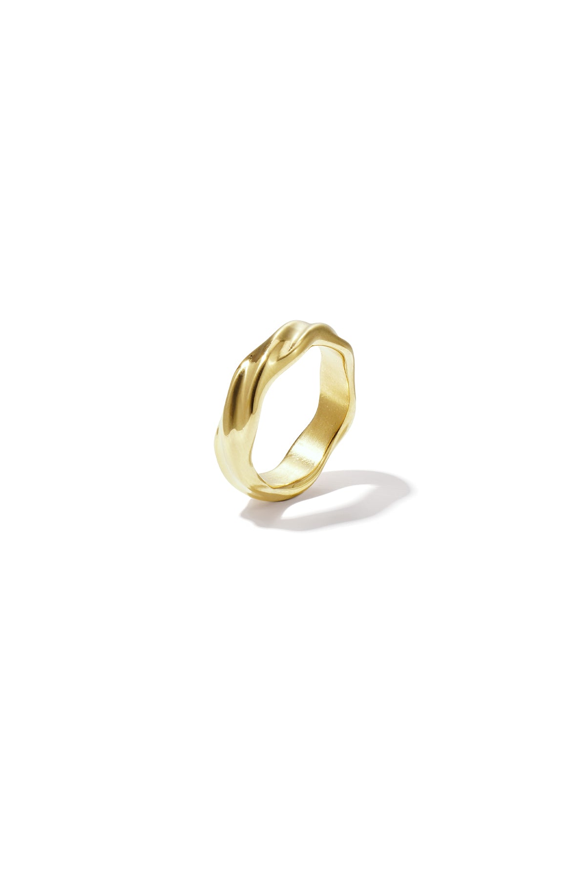 Close-up of a draped gold ring featuring a wavy, smooth design casting a soft shadow on a white background