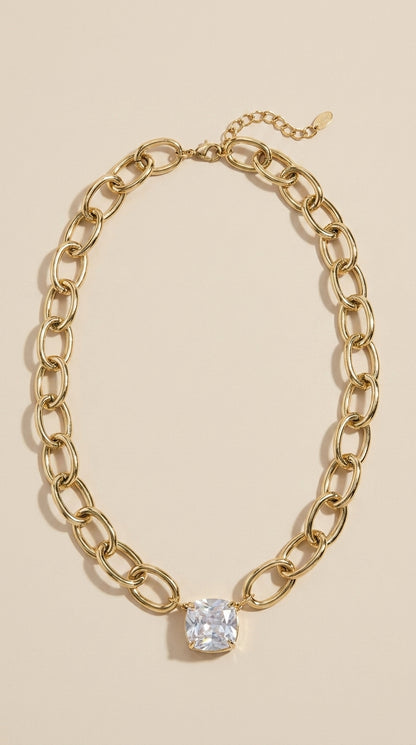 Gold chain necklace with a chunky oval link design and a sparkling square crystal pendant.