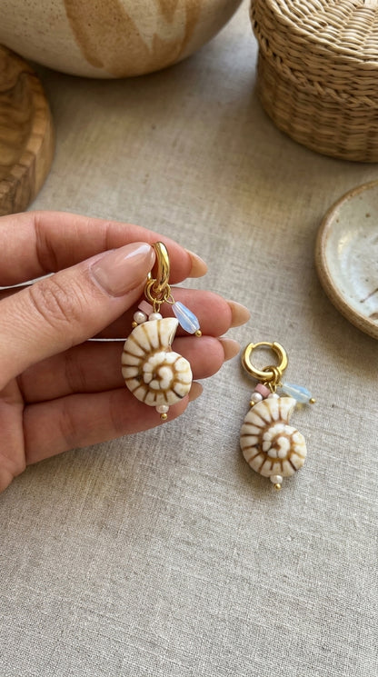 Shell Hoop Drop Era earrings: gold hoops with nautilus shell charms, small pearls, pink beads, and blue opalescent drops.