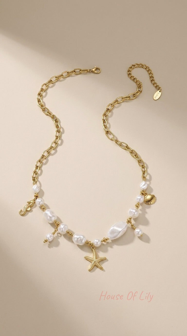 Gold chain necklace featuring baroque pearl beads and gold starfish, seahorse, and seashell charms.