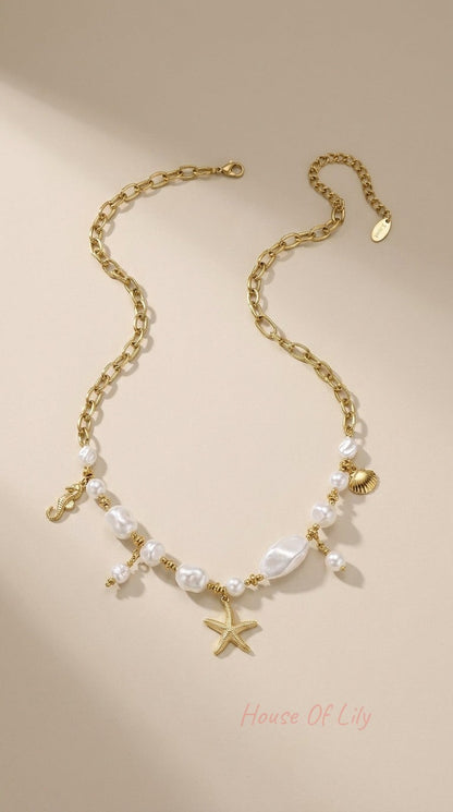 Gold chain necklace featuring baroque pearl beads and gold starfish, seahorse, and seashell charms.