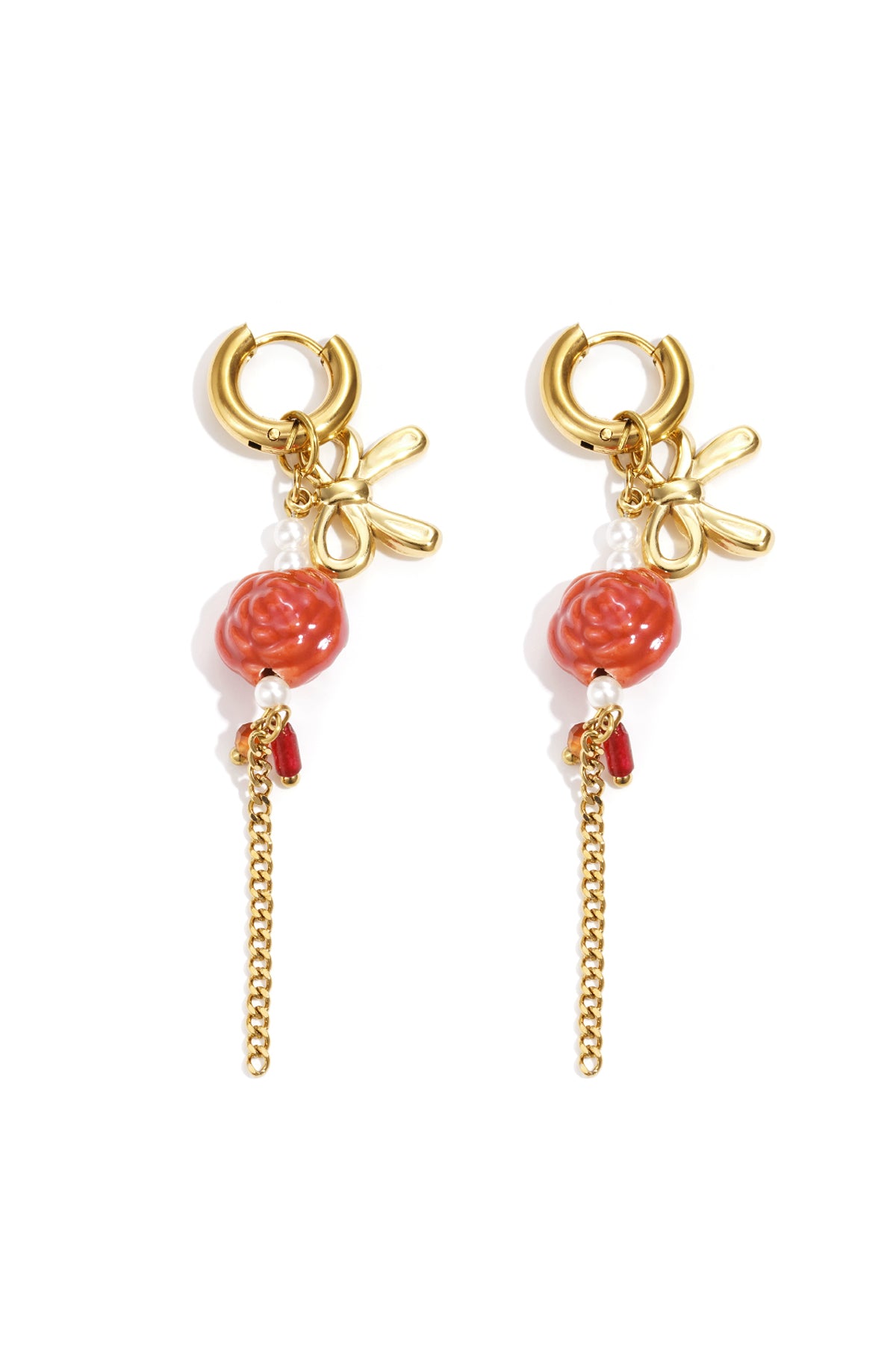 Pair of gold-tone floral drop earrings featuring bow motifs, orange flower beads, faux pearls, and dangling gold chains on white background