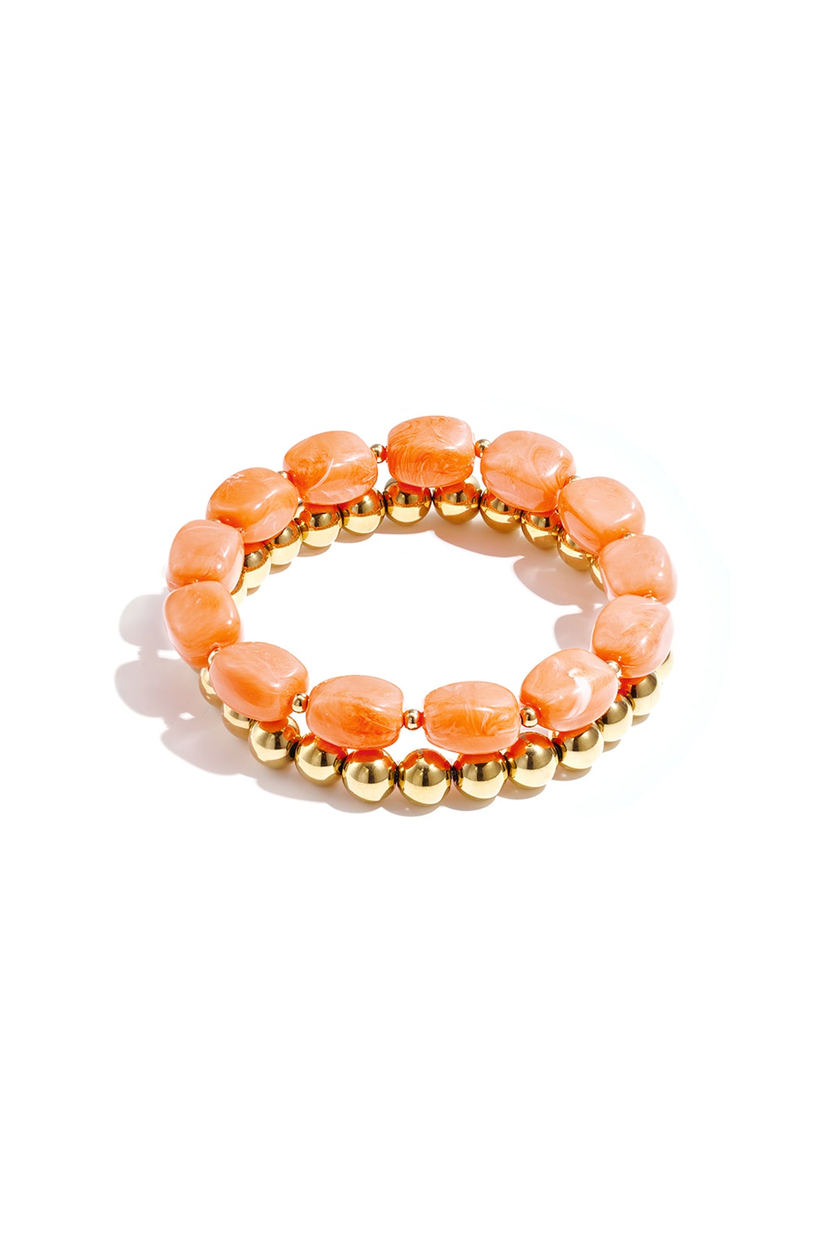 Close-up of a peach marbled acrylic beaded bracelet paired with a shiny gold-tone beaded bracelet on white background