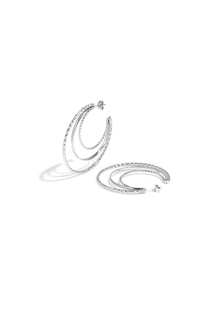 Layered triple hoop earrings in silver featuring two textured hammered hoops and a smooth middle hoop arranged on a white background