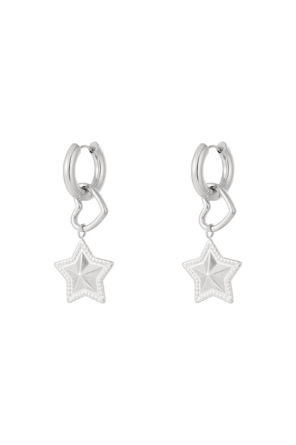 Pair of silver hoop earrings with dangling open heart and textured star charms on white background