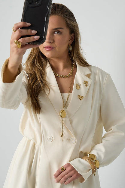 Model wearing the gold irregular pendant necklace styled with hoop earrings, rings, and bracelet, taking a selfie