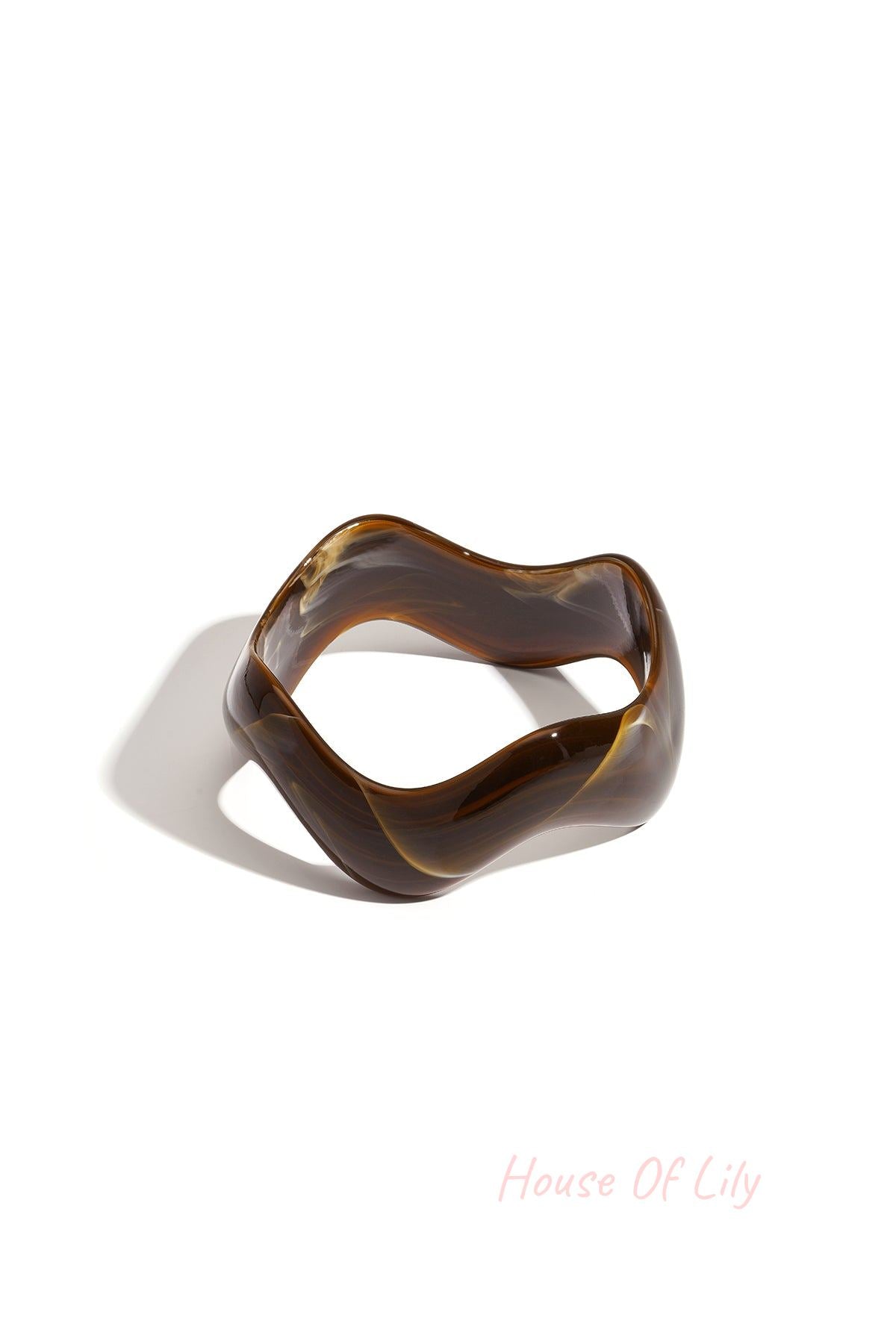 Brown acrylic bangle with marbled swirls and irregular shape cast in shadow on white background