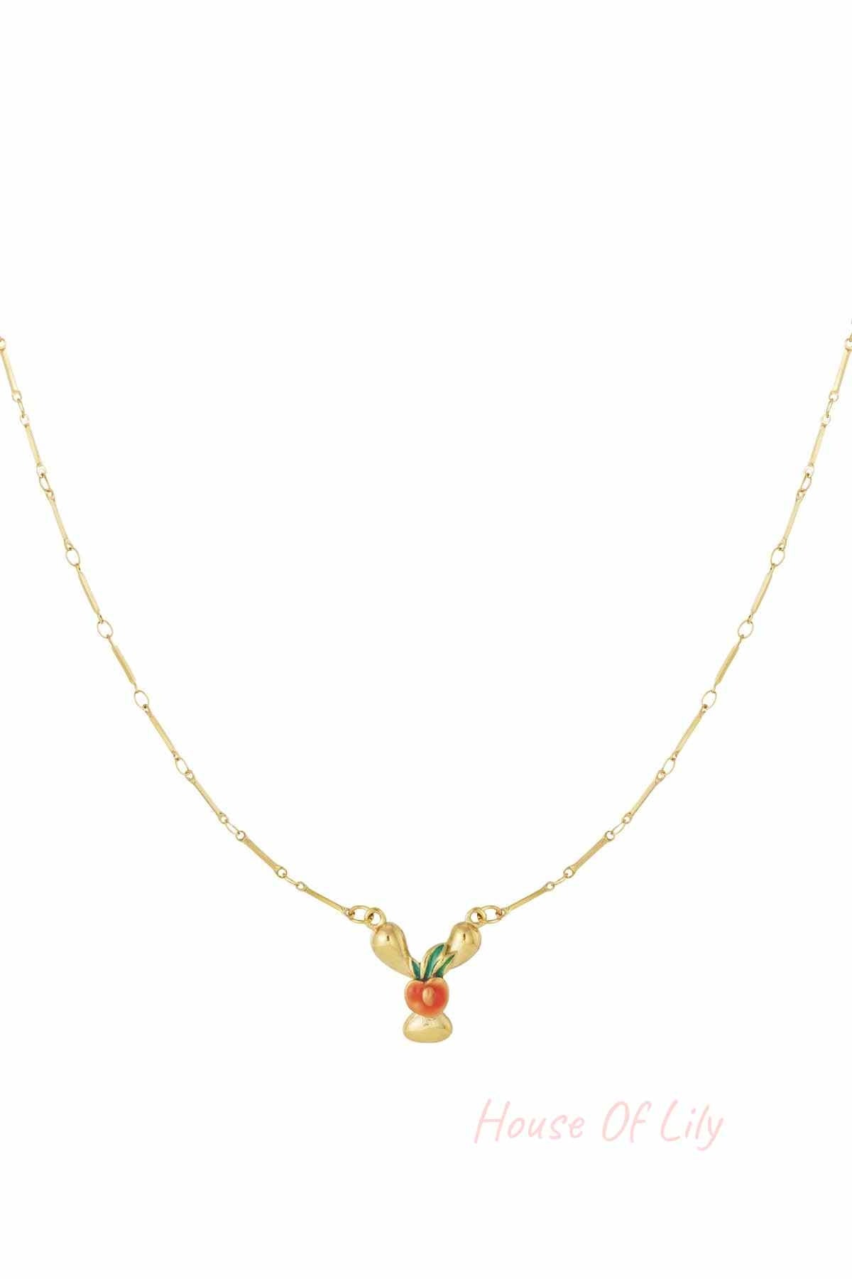 Gold chain necklace featuring a stylized, enamelled orange fruit charm with green leaves on a dainty gold link chain.