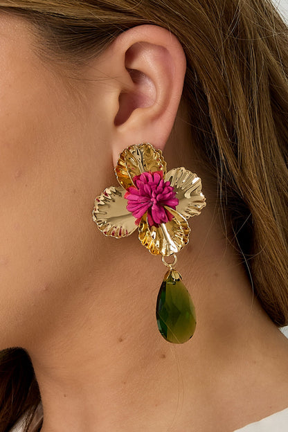 Side profile close-up showing gold floral earring with pink center and green teardrop pendant worn by woman with light hair